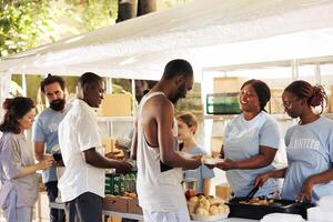 al aire libre comida distribución evento orquestado por sin ánimo de lucro, atrayendo individuos de todas Razas, complaciente a contribuir a bienestar de desamparado. voluntarios secundario el necesitado con calentar comidas. foto