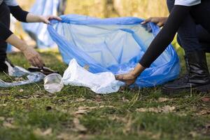 mujer voluntarios limpieza el bosque por cosecha arriba basura en bolsas, reciclaje el plastico residuos para un sostenible estilo de vida. personas coleccionar basura, trabajar como voluntario en contra contaminación. foto