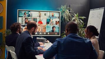 Business associates meeting with stakeholders on a videocall connection, sharing insight and updates on a new development project. Executive board members discussing about firm growth. Camera B. photo