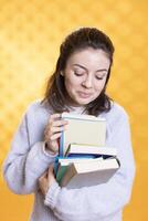 retrato de jubiloso mujer hojeada mediante apilar de libros, reunión información para colegio examen, estudio antecedentes. radiante estudiante hurgando mediante libros de texto montón, preparando para cursos foto