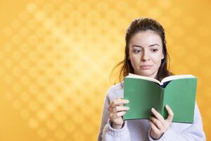 Woman turns page on book, opening eyes wide in amazement, enjoying story, conveying joy of reading concept, studio background. Geek astonished by surprising novel, showing appreciation for literature photo