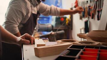 Woodworker using power drill to create holes for dowels in wooden board, close up. Carpenter sinks screws into wooden surfaces with electric tool, doing precise drilling for seamless joinery, camera B photo