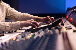 Audio expert uses mixing console and switchers on control room panel, adjusting sound on mixer. Music producer changes recording settings with technical equipment and soundboard. photo