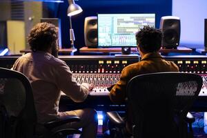 Singer and producer working together in professional music studio, collaborating on a hit song in control room. Audio engineer editing records with mixing and mastering techniques. photo