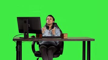 Young adult playing games on computer at desk against greenscreen backdrop, winning worldwide tournament on pc. Woman gamer feeling pleased and happy with her success. Camera B. photo