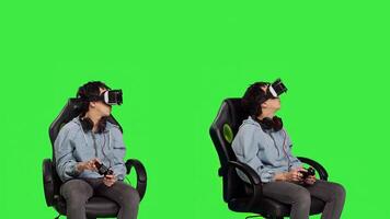 Woman playing games using virtual reality headset in studio, enjoying cyberspace 3d gaming tournament against greenscreen backdrop. Gamer having fun with vr glasses. Camera B. photo