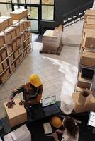 Diverse employees standing at counter desk in stockroom, preparing customer order for delivery. Storage room coworkers discussing merchandise quality control, working at inventory in warehouse photo