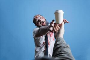 Person unable to function properly without coffee, trying to grab cup. Man fueled by caffeine, needing it to function and be a productive obedient worker, studio background photo