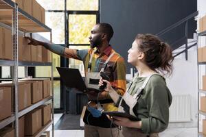 Diverse storehouse employees checking cardboard boxes, scanning products for inventory using store scanner in warehouse. Stockroom supervisors working at clients orders preparing packages for delivery photo