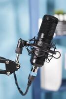 Professional black microphone for internet channel audio podcast live streaming. Mic equipment close up for sound and communication recording on radio in modern empty studio photo