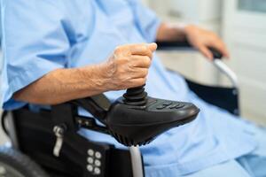 Asian senior woman patient on electric wheelchair with remote control at hospital, healthy strong medical concept. photo