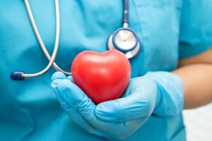 médico sosteniendo un corazón rojo en la sala del hospital, concepto médico fuerte y saludable. foto