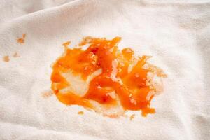 mancha de salsa de tomate sucia o ketchup en tela para lavar con detergente en polvo, limpieza del concepto de tareas domésticas. foto