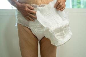 asiático mayor mujer paciente vistiendo incontinencia pañal en hospital, sano fuerte médico. foto