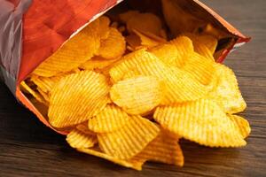 Potato chips, delicious BBQ seasoning spicy for crips, thin slice deep fried snack fast food in open bag. photo