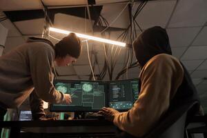 Hackers team hacking online server, stealing data, cybercrime. Cyberattack, it specialist pointing at code on pc screen, criminals programming internet virus at night time photo