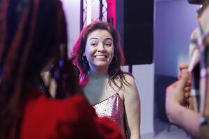 Smiling cheerful woman partying with friends and socializing at nightclub discotheque. Carefree happy girl clubbing and attending disco social gathering event, enjoying nightlife leisure photo