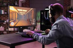 Pro gamer competing in intense online multiplayer game, broadcasting esports tournament live from brick wall apartment. Man using expert level gaming mouse and keyboard for perfect accuracy photo