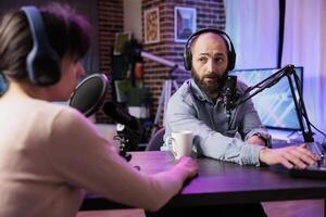 Show presenter interviewing designer during live stream, talking about fashion and style trends. Man having conversation with social media influencer, recording episode for podcast photo