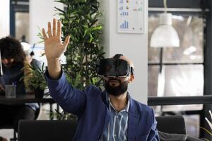 Businessman in virtual reality headset working in start up business office. Company employee exploring metaverse and brainstorming in vr glasses in corporate coworking space photo