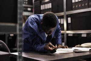 africano americano gerente lluvia de ideas ideas mientras trabajando a contabilidad investigación, analizando teneduría de libros informe. empresario buscando para administrativo grabar trabajando tiempo extraordinario en archivar habitación. foto