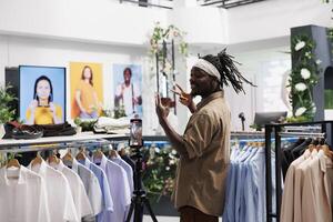 African american influencer promoting latest clothing collection in store. Man blogger recording with apparel brand advertising to share through social media accounts photo