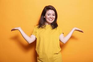 Delighted, thrilled woman with extended arms, brown hair, and a big smile stands against isolated orange background. She exudes happiness and contentment and radiates positive emotions. photo