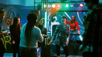 personas teniendo divertido a danza fiesta, ir de fiesta juntos en electrónico música a discoteca. alegre grupo de amigos disfrutando noche fuera a club, bailando alrededor para entretenimiento. Mano disparo. foto