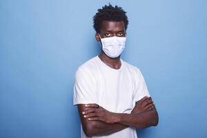 Portrait of african american man wearing face mask to protect from coronavirus in studio. Close-up of black male individual looking at camera while having protective mask on face. photo