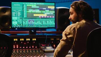 Team of artist and technician editing audio after recording session in control room, mixing and mastering tracks on console in control room. Pressing buttons and pushing sliders. Camera A. photo