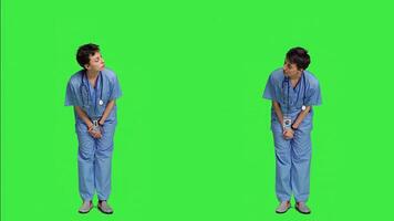 Medical assistant being impatient against greenscreen backdrop, looking around and waiting for patients at consultations. Nurse with health expertise feeling frustrated while she waits. Camera A. photo