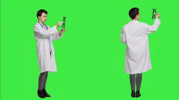 General practitioner examining radiography scan against greenscreen backdrop, looking at x ray results to find diagnosis. Physician in white coat uses radiology science and research. Camera A. photo