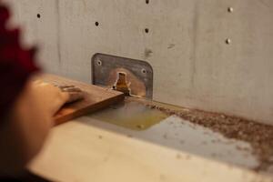 Man at workbench putting lumber block though spindle moulder, doing furniture assembling. Joiner using heavy machinery to perform various manufacturing tasks, enjoying diy hobby, close up shot photo