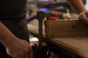 Carpenter using bench vise to hold timber block, starting furniture assembling in workshop, close up shot. Manufacturer in joinery using vice tool to grip piece of wood before carving it photo