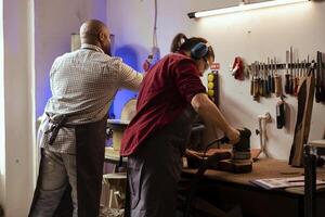 Maestro carpintero y aprendiz utilizando orbital lijadora en Tablas de madera, montaje mueble. trabajo en equipo empleados en montaje tienda utilizando ángulo amoladora a crear de madera decoraciones, refinando madera objetos foto