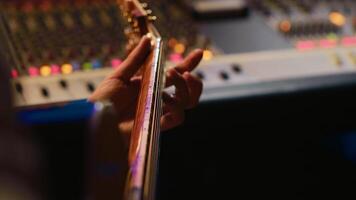 Musician singer recording a new song on his electro acoustic guitar, creating new music in professional studio control room. Artist doing live performance with instrument. Close up. Camera A. photo