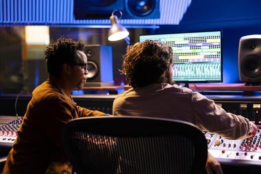 Team of technical engineers working on recording and editing music in professional studio, collaborating on mix and master audio files to create a new hit song. Artist and expert in control room. photo