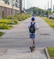 Disparo de el chico montando eléctrico scooter en el calles concepto foto