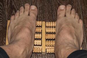 Shot of the man using feet massager to improve flatfoot. Healthcare photo