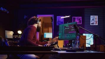 Soundtrack producer adjusts and mixes additional sounds to audio files while changing noise settings, using an USB stick. Artist plays piano and uses a mixing console and audio plug ins. Camera B. photo