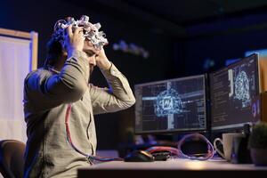 Computer scientist puts EEG headset on, starting mind upload process, trying to gain bionic powers. Man using high tech neuroscientific gear to transfer consciousness into cyberspace photo