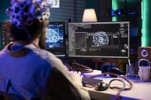 Software technician using EEG headset gear translating thoughts into PC commands using brainwave signals. IT specialist controlling computer functions using mind, helped by scifi technology photo