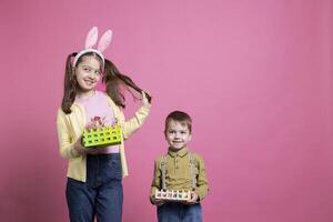 positivo linda niños presentación festivo hecho a mano adornos en cámara, sensación alegre acerca de Pascua de Resurrección fiesta evento y primavera tiempo. hermano y hermana espectáculo su cestas con pintado huevos. foto