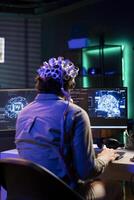 Software technician with EEG headset on programming brain transfer into computer virtual world, merging with artificial intelligence. IT expert using neuroscience to gain digital soul photo