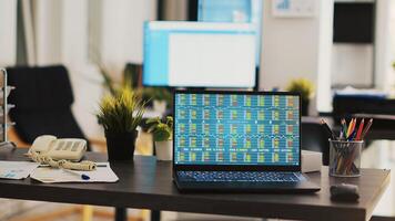 Desk in empty office with laptop showing stock exchange data collected to develop trading strategies. Forex analytics on notebook screen in company workplace showing trading platform photo