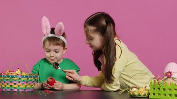 Ecstatic kids breaking a special easter egg to find a surprise inside, feeling curious about a festive decoration that transforms in a plant. Cheerful little children having fun in studio. Camera A. photo