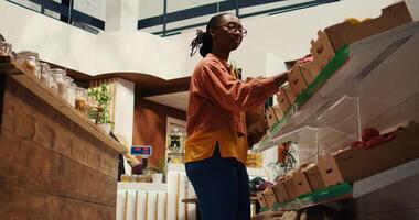 regular cliente poniendo bio de cosecha propia vegetales en un papel bolsa, yendo tienda de comestibles compras a cero residuos eco almacenar. mujer secundario pequeño negocio y sostenible estilo de vida. cámara 2. trípode disparo. foto