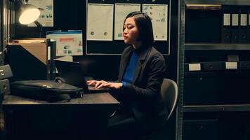 Private officer sitting at workstation to develop profiles of potential suspects based on archived data, using forensic techniques to examine evidence in the archive. Criminology expert. Camera A. photo