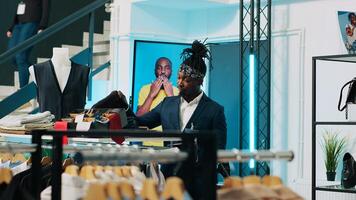 Regular elderly client asking store worker for assistance with clothing items, looking for a shirt to go with his suit jacket. African american clerk managing inventory and helping shopper. Camera A. photo