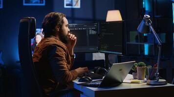 Developer typing code in home office, using Java programming language to develop software application. It professional using multimonitor PC setup and laptop to finish tasks, camera A photo